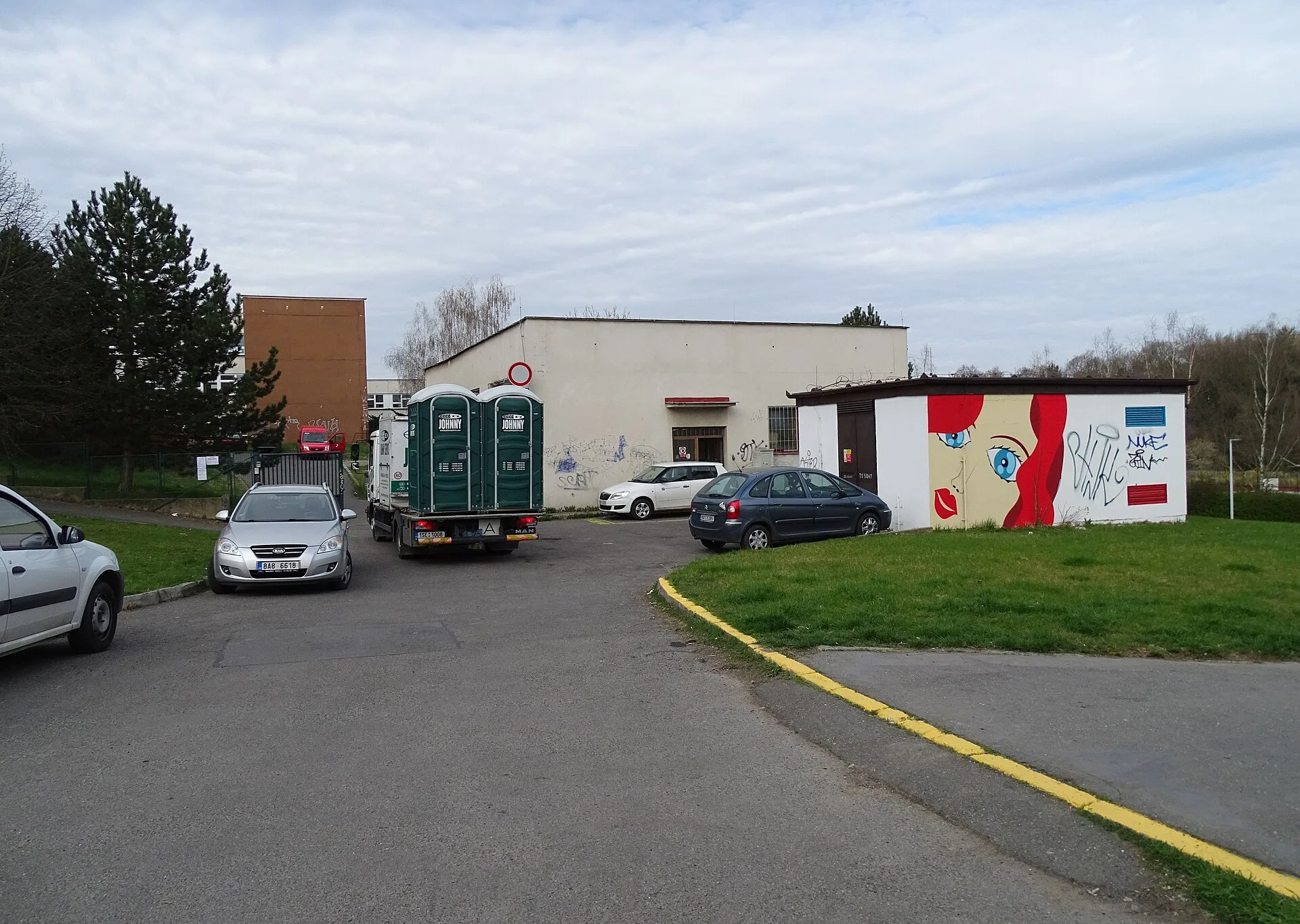Prague - Modřany , Czech Republic . Rakovského street, a truck with portable toilets, a distribution electrical station with murals. Disaster surge operations for portable restroom fleets