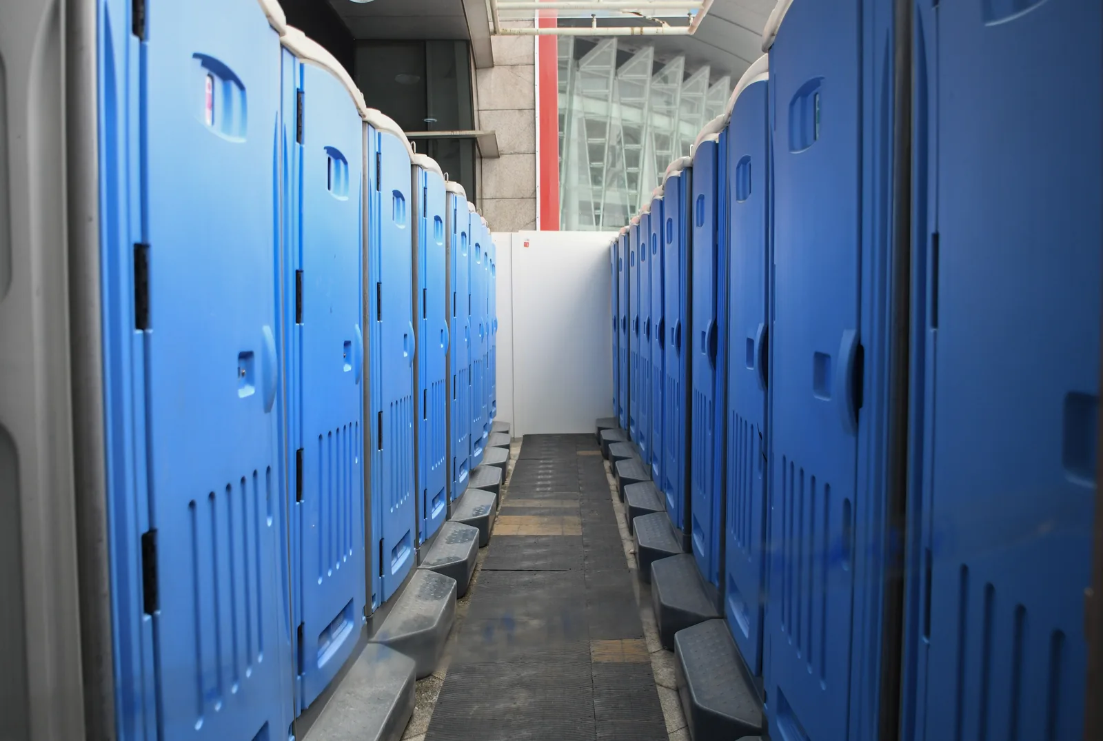 A series of blue portable toilets aligned at an outdoor construction site. Portable restroom rental business: what comes first