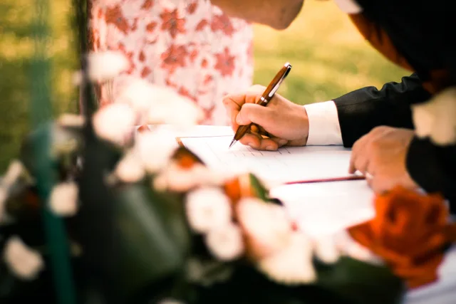 A close-up of hands signing a marriage contract during an outdoor wedding ceremony. Portable Restroom Rental Contracts: Clauses That Protect Your Fleet